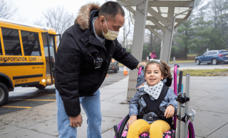 child in wheelchair with teacher's aide