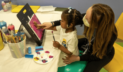preschooler finger painting with occupational therapist