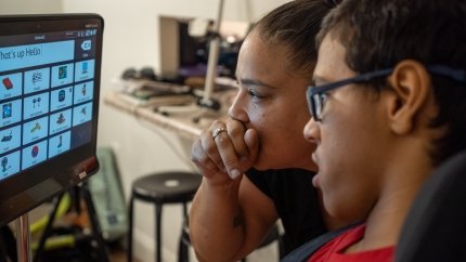 mom and son looking at augmentative communication device