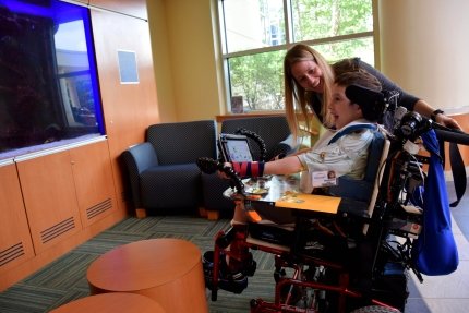 child in wheelchair with therapist