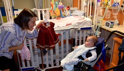 baby with clothing being shown to her 