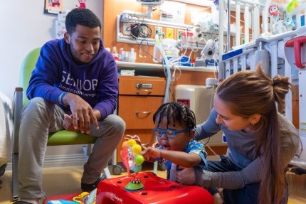 Occupational Therapist providing therapy to baby while brother looks on