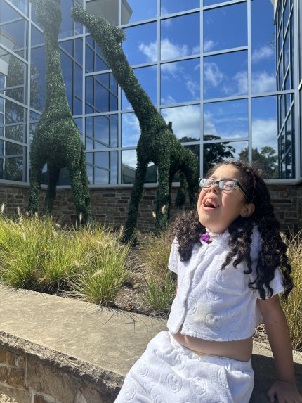 young girl sunning herself next to giraffe topiaries