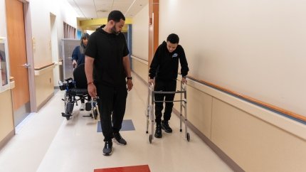 Teenage boy walking with walker and father
