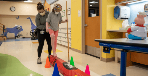 child and therapist on balance beam