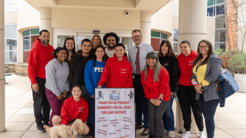 Group of people standing in front of hospital with sign